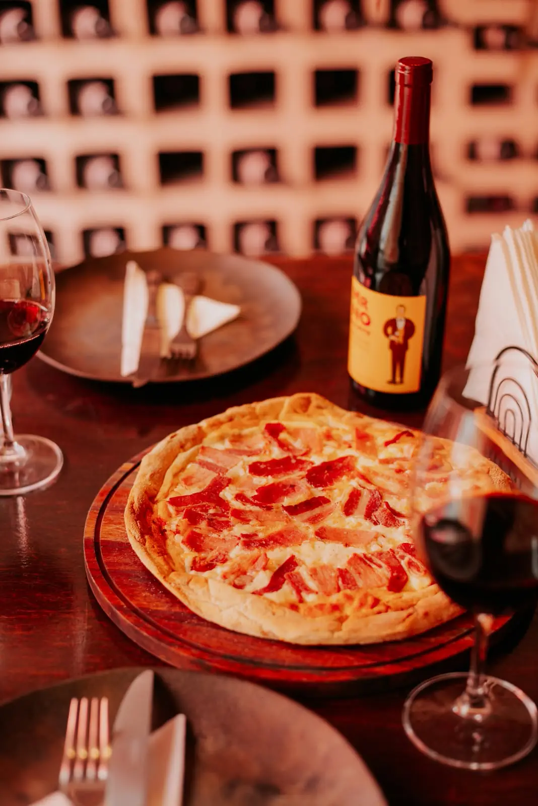 Pizza de calabresa na mesa com vinho tinto e taças