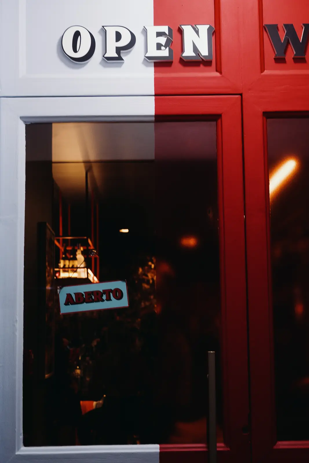 Porta de vidro com a plaquinha "Aberto" sob o letreiro Open Wine Store