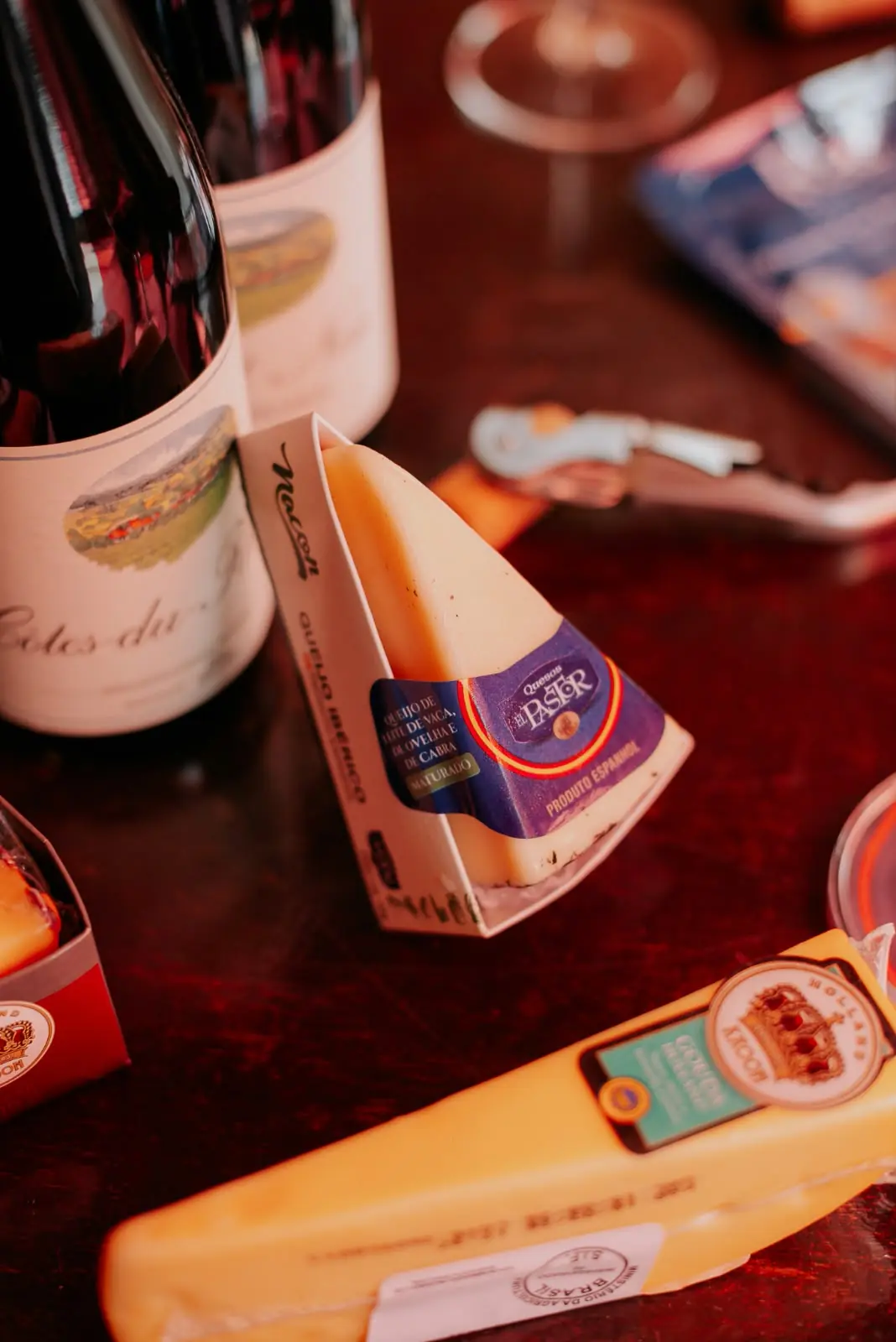 Queijos e garrafas de vinho sobre a mesa de madeira